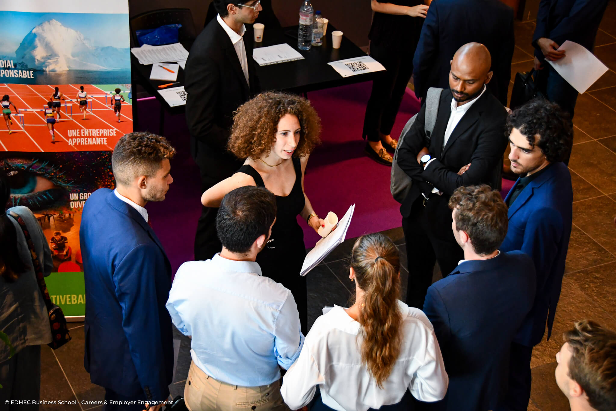 Groupe d'étudiants en cercle discutant avec une recruteuse tenant des CV dans sa main