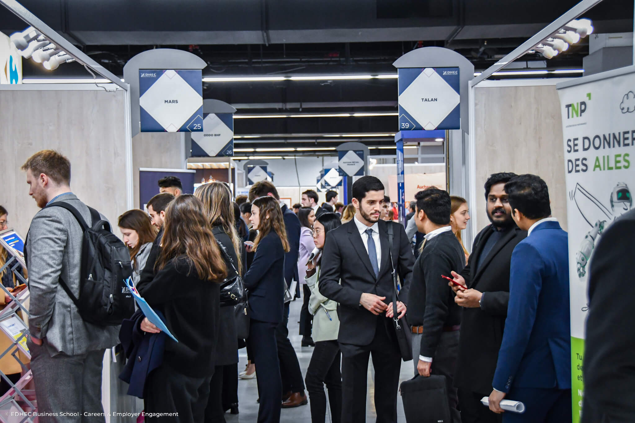 Etudiants se tenant devant des stands d'entreprises lors du Forum EDHEC