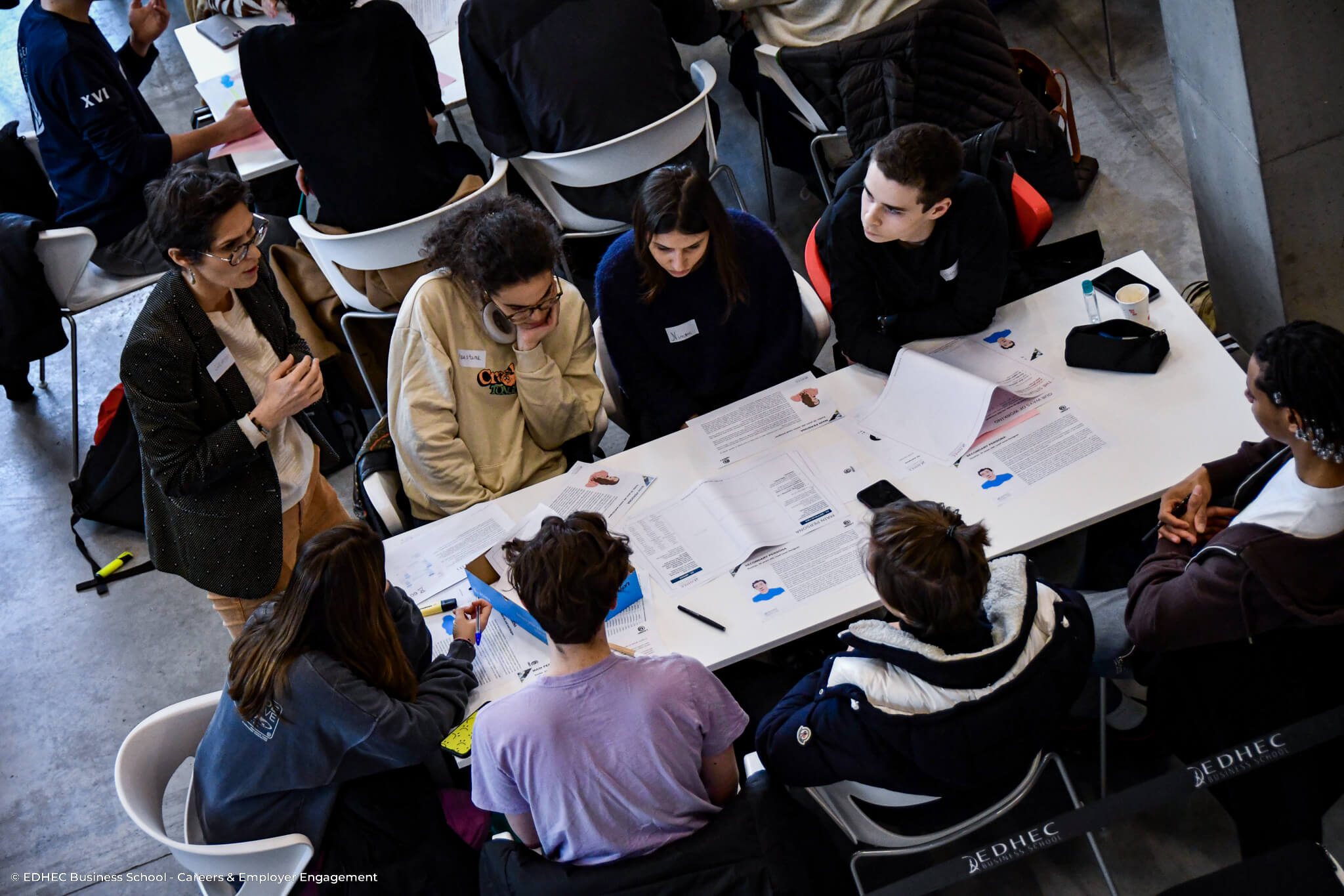 Six étudiants assis autour d'une table écoutant une facilitatrice lors d'un atelier de groupe